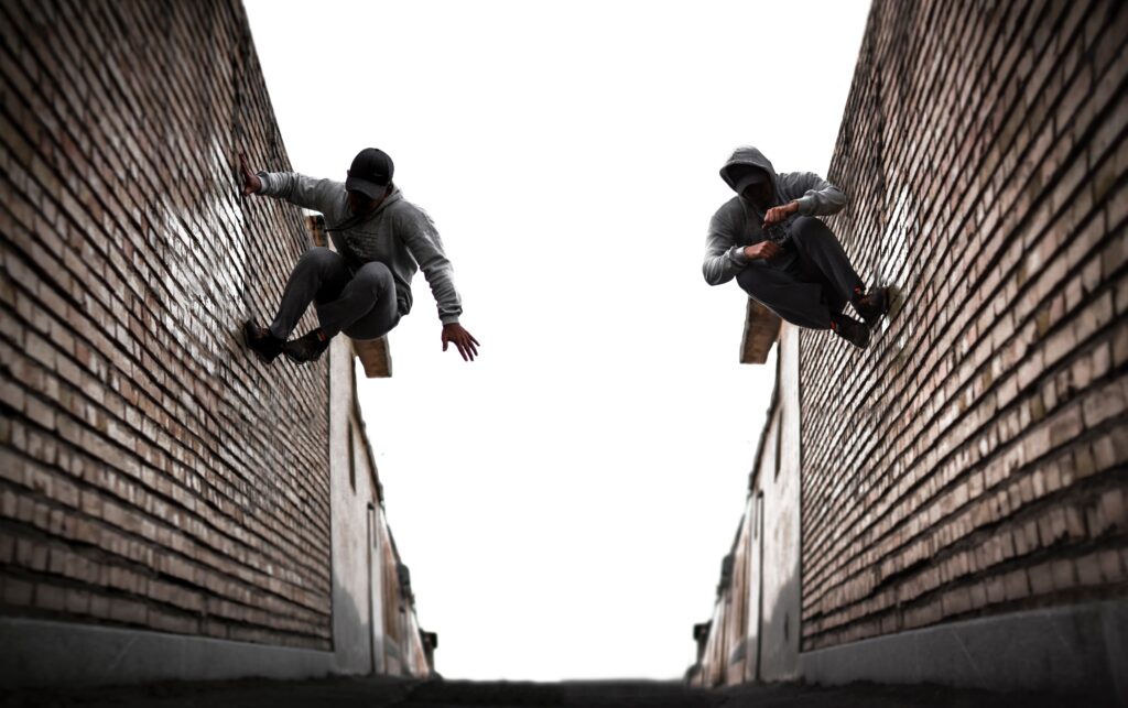 deux hommes en train de sauter sur un mur _ parkour