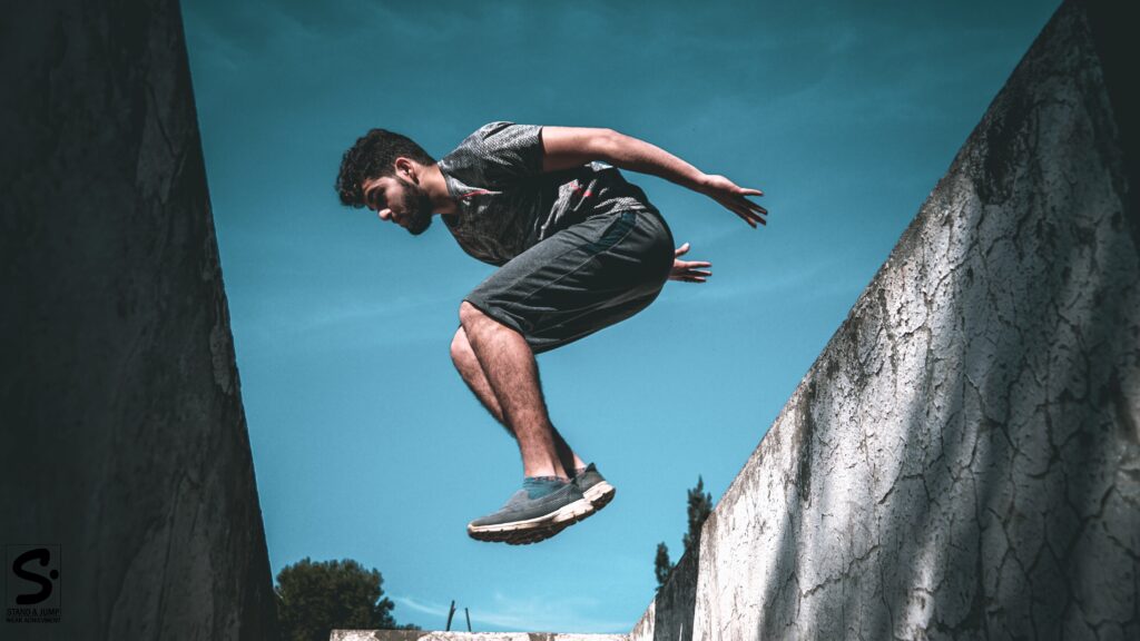 Personne en train de sauter un muret, en train de faire du parkour